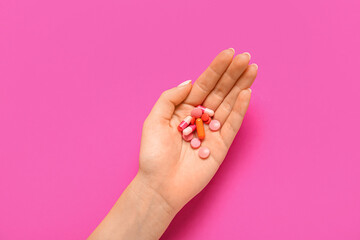 Female hand with different pills on pink background