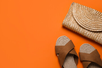 Stylish brown sandals and wicker bag on orange background - obrazy, fototapety, plakaty
