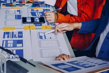 Close up ux developer and ui designer brainstorming about mobile app interface wireframe design on...
