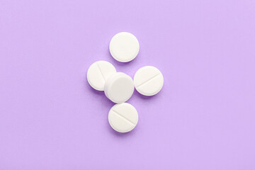 White medical pills on purple background