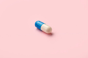 Medical capsule on pink background, closeup