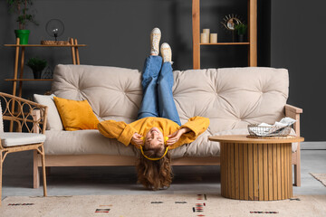 Young woman in headphones relaxing on sofa at home