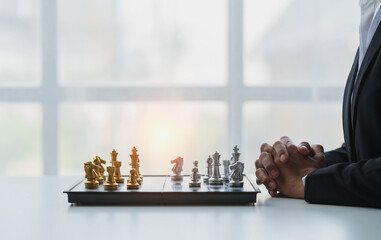 young businessman Asian man sitting holding hands looking at a chess set Business strategy concepts, business plans, teamwork Success management or leadership concept. - obrazy, fototapety, plakaty