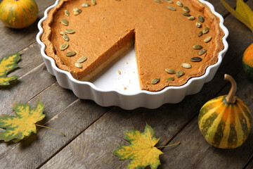 Baking dish with tasty pumpkin pie on wooden background