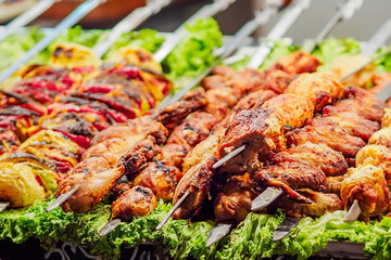 Shashlik. Baked meat on skewer with herbs. Delicious healthy lunch. Closeup of grilled meat on fire.