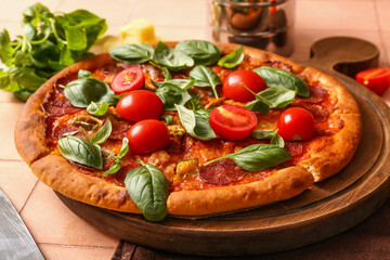 Wooden board of delicious Pepperoni pizza with tomatoes and basil on pink tile background