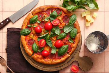 Wooden board of delicious Pepperoni pizza with tomatoes and basil on pink tile background
