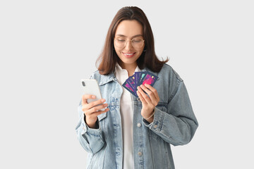 Young woman with credit cards and mobile phone on white background. Online shopping