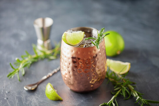 Moscow mule cocktail in a copper cup with lime, ginger beer, vodka and rosemary garnish
