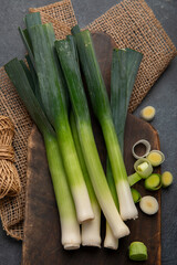 Cut fresh leeks on wooden board. Dark background.