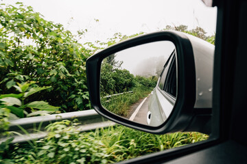 Landscape in the sideview mirror of a car on countryside road