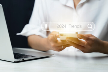 Touching to search engine bar with 2024 trends wording for marketing monitor and business planing...