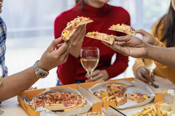 Group of happy Asian young people with friends celebrate clinking glasses during party, food, pizza, snacks with silverware Stemware glass and delicious food
