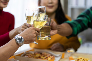 Group of happy Asian young people with friends celebrate clinking glasses during party, food, pizza, snacks with silverware Stemware glass and delicious food