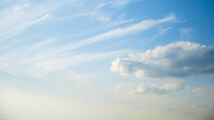 The wind was blowing the fluffy white clouds across the bright blue sky, creating a motion in the atmosphere.