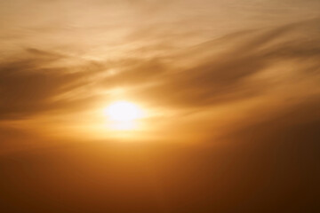 Sunset sky with red light of the setting sun. Evening clouds in the orange light of sunset rays