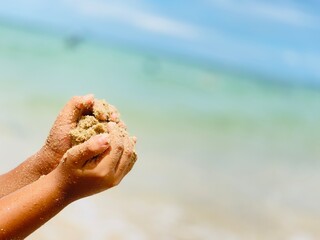 The boy is happily playing with sand in the sea.