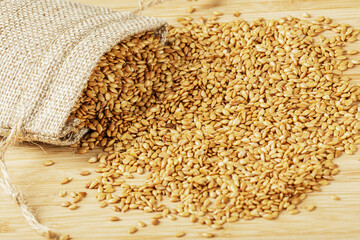 Burlap bag of Roasted Flax Seeds isolated on wooden background