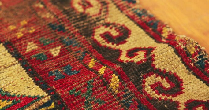 Macro shot of an old shabby handmade carpet made by Samarkand masters using ancient technology. It is covered with national patterns and ornaments. Uzbekistan.