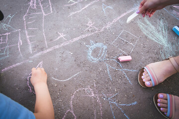 Children draw with chalk on the road. Children's creativity on the street.