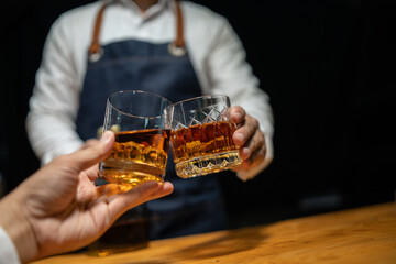 Bartender pours whiskey to customer in tavern