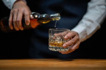 Bartender pours whiskey to customer in tavern