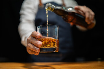 Bartender pours whiskey to customer in tavern - obrazy, fototapety, plakaty