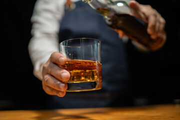 Bartender pours whiskey to customer in tavern