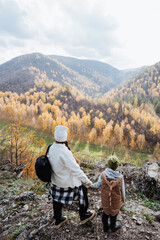 Fototapeta na wymiar Family vacation in nature, mother and son walking in the mountains, hiking in the autumn forest, school holidays, trekking in the mountains.