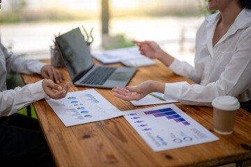 Focusing on data, two businesswomen talk at the table and brainstorm business ideas. Providing advice and marketing planning