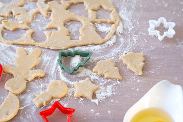 Obraz na płótnie Canvas Layout of cookie cutters close-up cut out cookies from the dough with molds on a Christmas theme in the form of a snowman, a Christmas tree, stars in the kitchen
