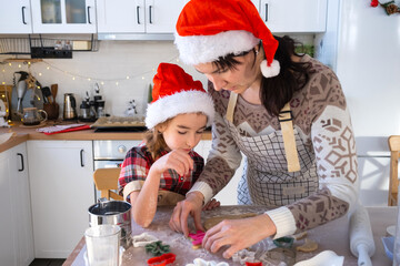Mom and daughter in the white kitchen are preparing cookies for Christmas and new year. Family day, preparation for the holiday, learn to cook delicious pastries, cut shapes out of dough with molds
