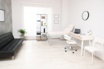 Blurred view of modern medical office with doctor's workplace and examination table in clinic