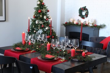 Elegant Christmas table setting with dishware and burning candles in festively decorated room
