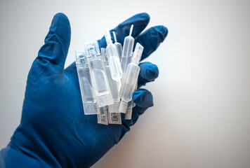 A hand in a rubber glove with plastic ampoules of an antibiotic. Medications in the doctor's hand....