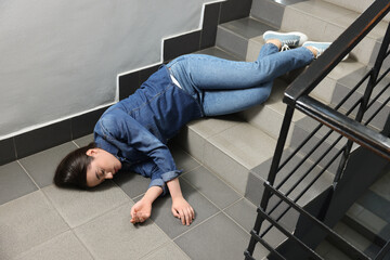 Unconscious woman lying on floor after falling down stairs indoors © New Africa