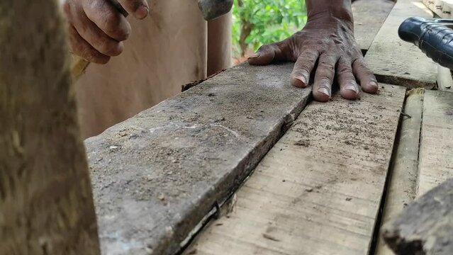 Old worker installing wooden planks to create a traditional house outdoor room