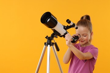 Happy little girl looking at stars through telescope on orange background, space for text