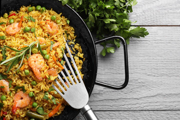 Tasty rice with shrimps and vegetables served on grey wooden table, flat lay. Space for text