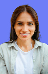 Portrait of a beautiful young brunette woman smiling against a blue background.