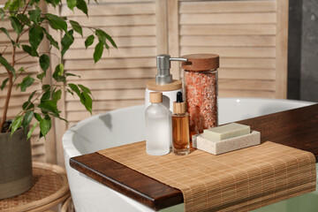 Fototapeta na wymiar Wooden tray with spa products on bath tub in bathroom