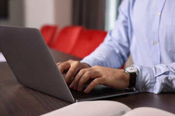 Man working on laptop at table in office, closeup