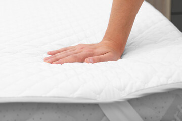 Man touching soft mattress with protector, closeup