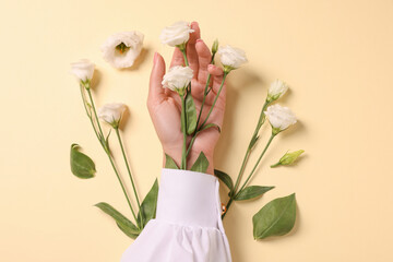 Woman with eustoma flowers on beige background, top view