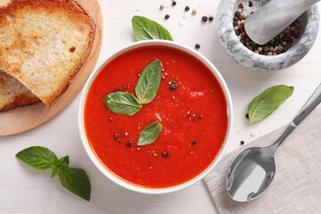 Flat lay composition with delicious tomato cream soup in bowl on white wooden table