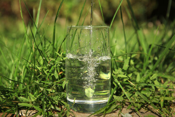 Pouring pure water into glass outdoors on sunny day