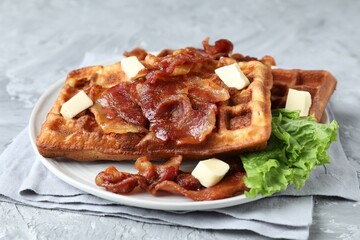 Delicious Belgium waffles served with fried bacon and butter on grey table, closeup