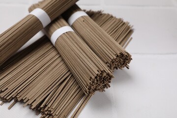 Uncooked buckwheat noodles (soba) on white table, closeup