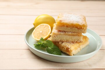 Tasty lemon bars with powdered sugar and mint on wooden table, closeup