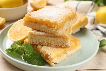Tasty lemon bars with powdered sugar and mint on table, closeup